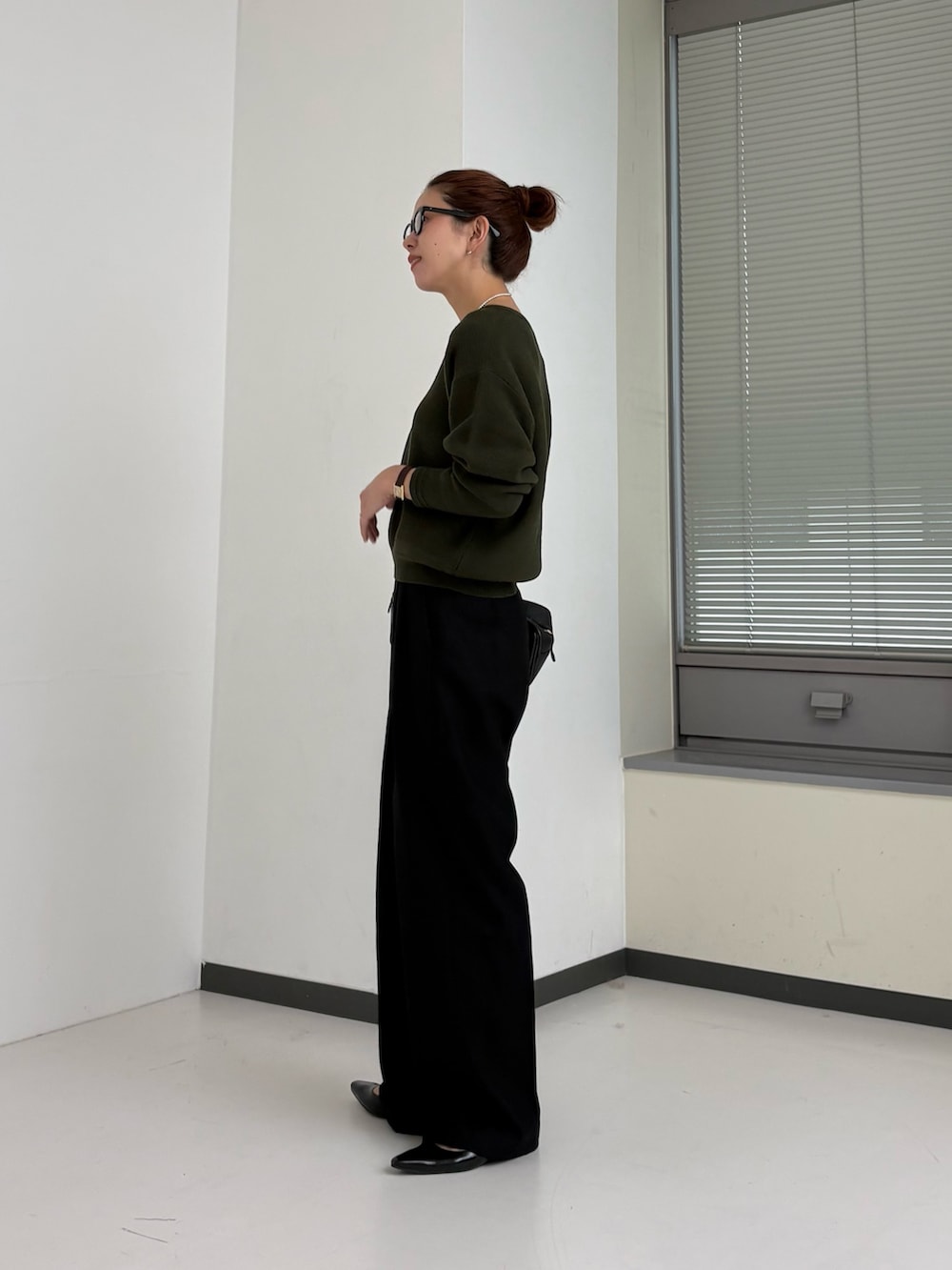 グリーン系のニット/セーター、ホワイト系のTシャツ/カットソー、ブラウン系のハンドバッグを着用したレディースの秋コーディネートの3枚目の写真