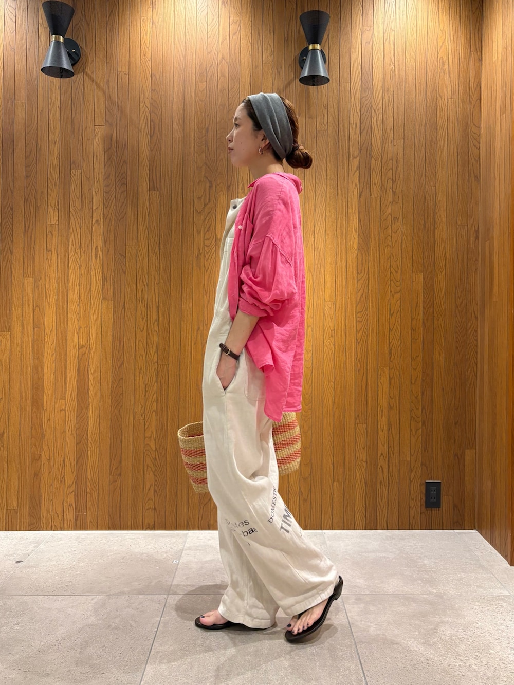 ベージュ系のその他パンツ、ベージュ系のかごバッグ、ブラウン系のサンダルを着用したレディースの夏コーディネートの2枚目の写真