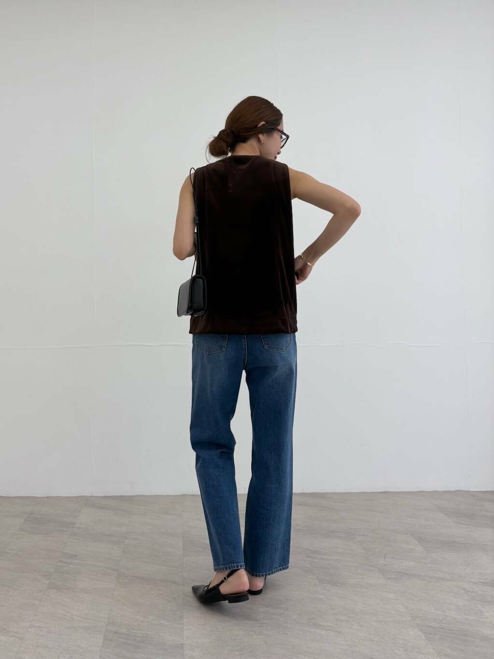 ブラック系のショルダーバッグ、ブラック系のパンプス、ブルー系のデニムパンツを着用したレディースの夏コーディネートの4枚目の写真