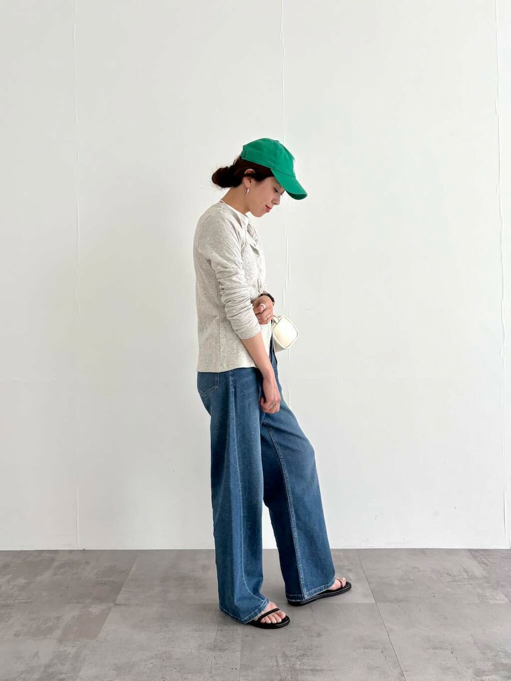 グレー系のカーディガン/ボレロ、ブルー系のデニムパンツ、ホワイト系のショルダーバッグを着用したレディースの春コーディネートの2枚目の写真