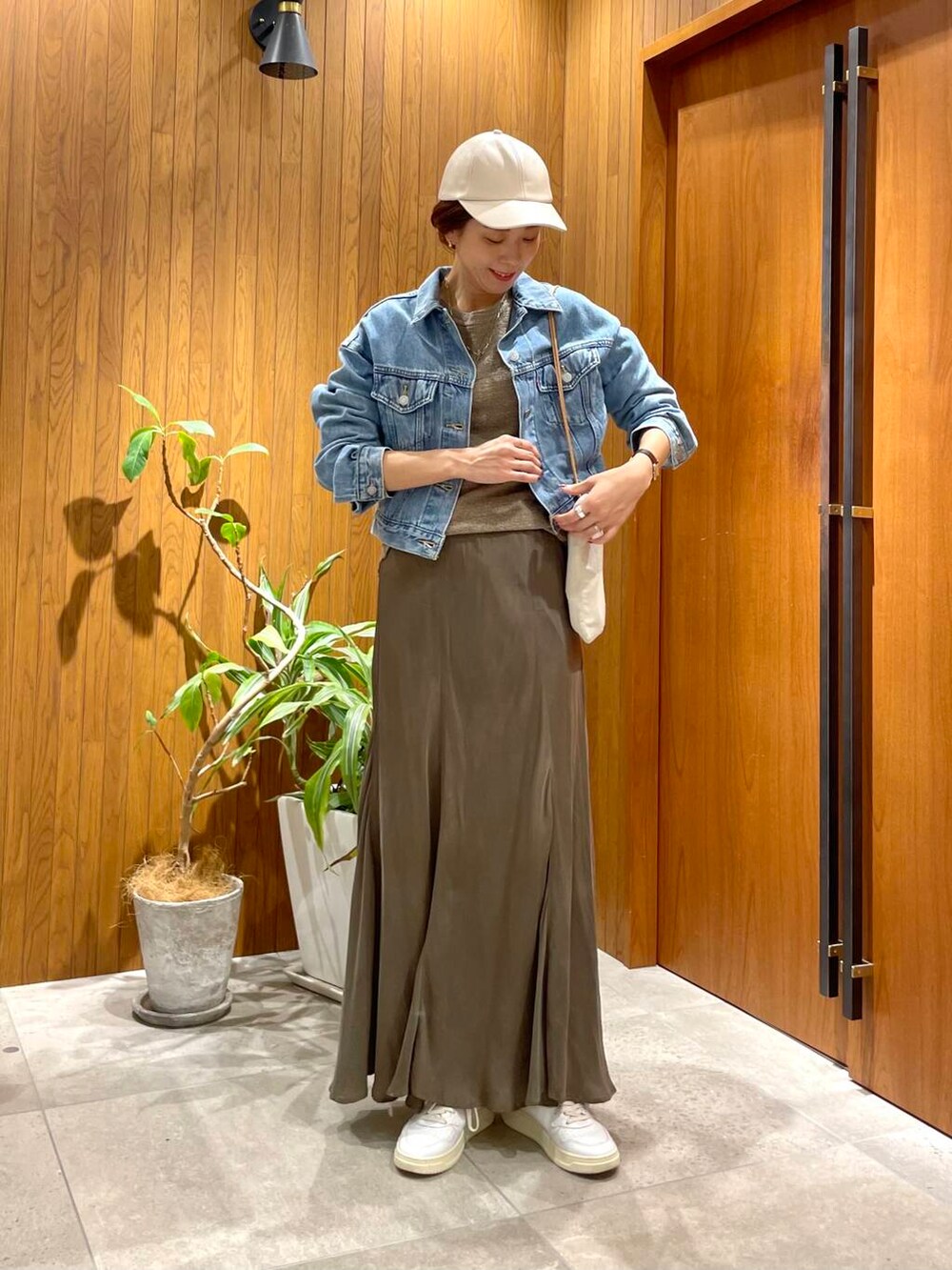 グリーン系のスカート、ブルー系のデニムジャケット、ホワイト系のスニーカーを着用したレディースの秋コーディネートの4枚目の写真