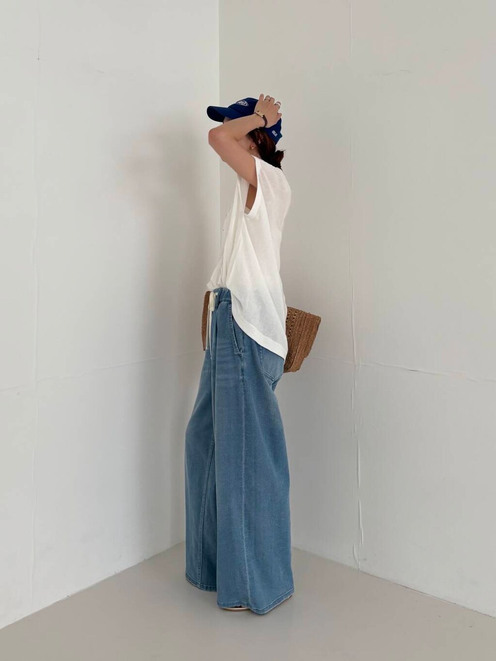 ホワイト系のキャミソール、ブルー系のデニムパンツ、ホワイト系のニット/セーターを着用したレディースの夏コーディネートの4枚目の写真