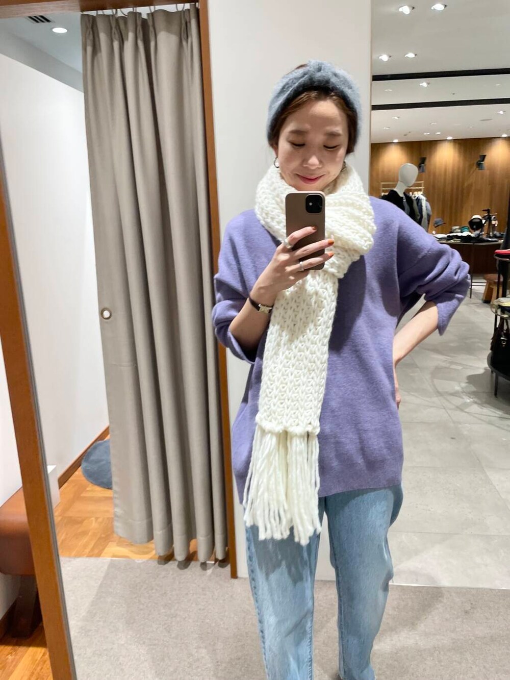 ブルー系のデニムパンツ、ベージュ系のブーツ、パープル系のニット/セーターを着用したレディースの冬コーディネートの4枚目の写真