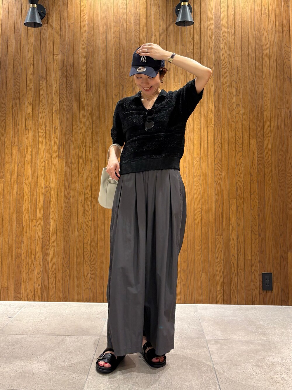 グレー系のその他パンツ、ブラック系のニット/セーター、ホワイト系のハンドバッグを着用したレディースの春コーディネートの4枚目の写真