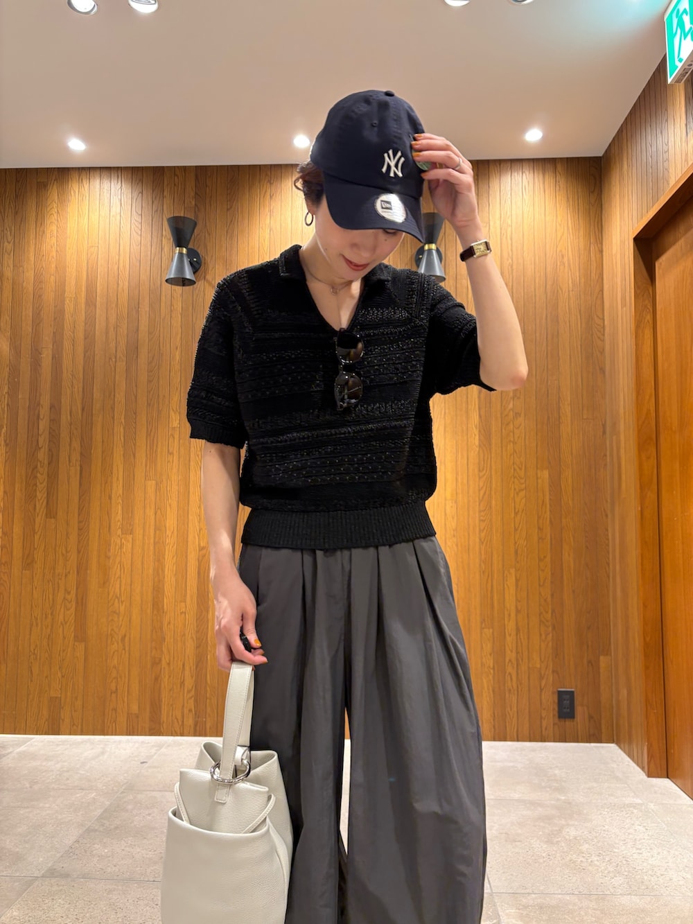 グレー系のその他パンツ、ブラック系のニット/セーター、ホワイト系のハンドバッグを着用したレディースの春コーディネートの6枚目の写真