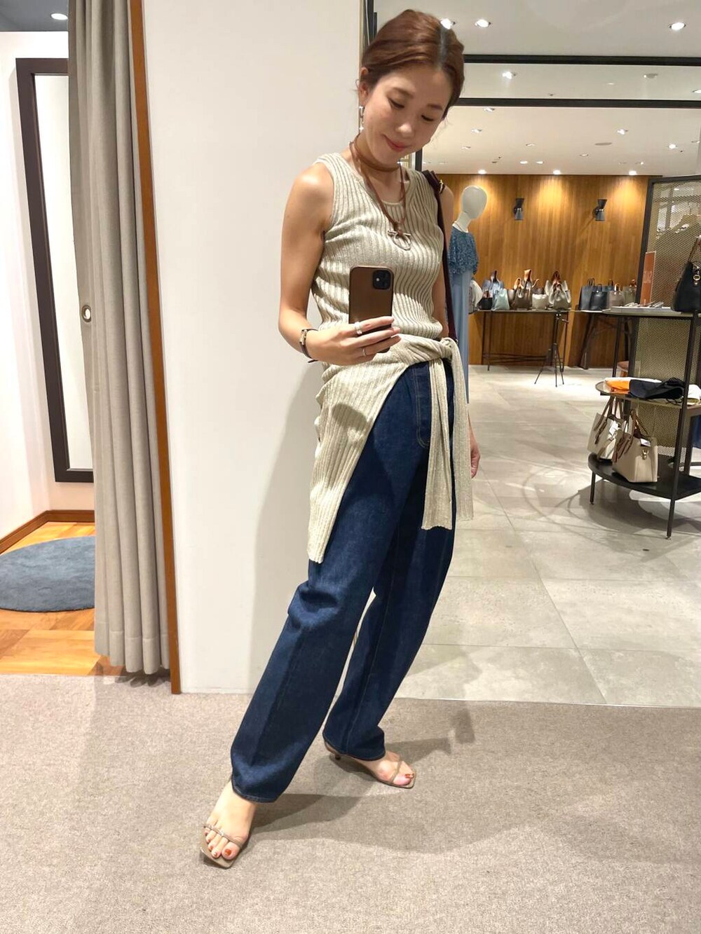 ベージュ系のカーディガン/ボレロ、ベージュ系のタンクトップ、ブルー系のデニムパンツを着用したレディースの夏コーディネートの2枚目の写真