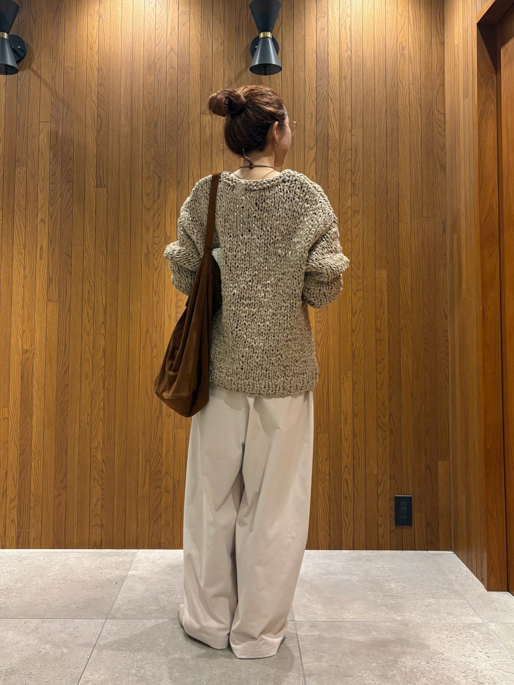 グレー系のニット/セーター、ホワイト系のその他パンツ、ブラウン系のトートバッグを着用したレディースの秋コーディネートの3枚目の写真