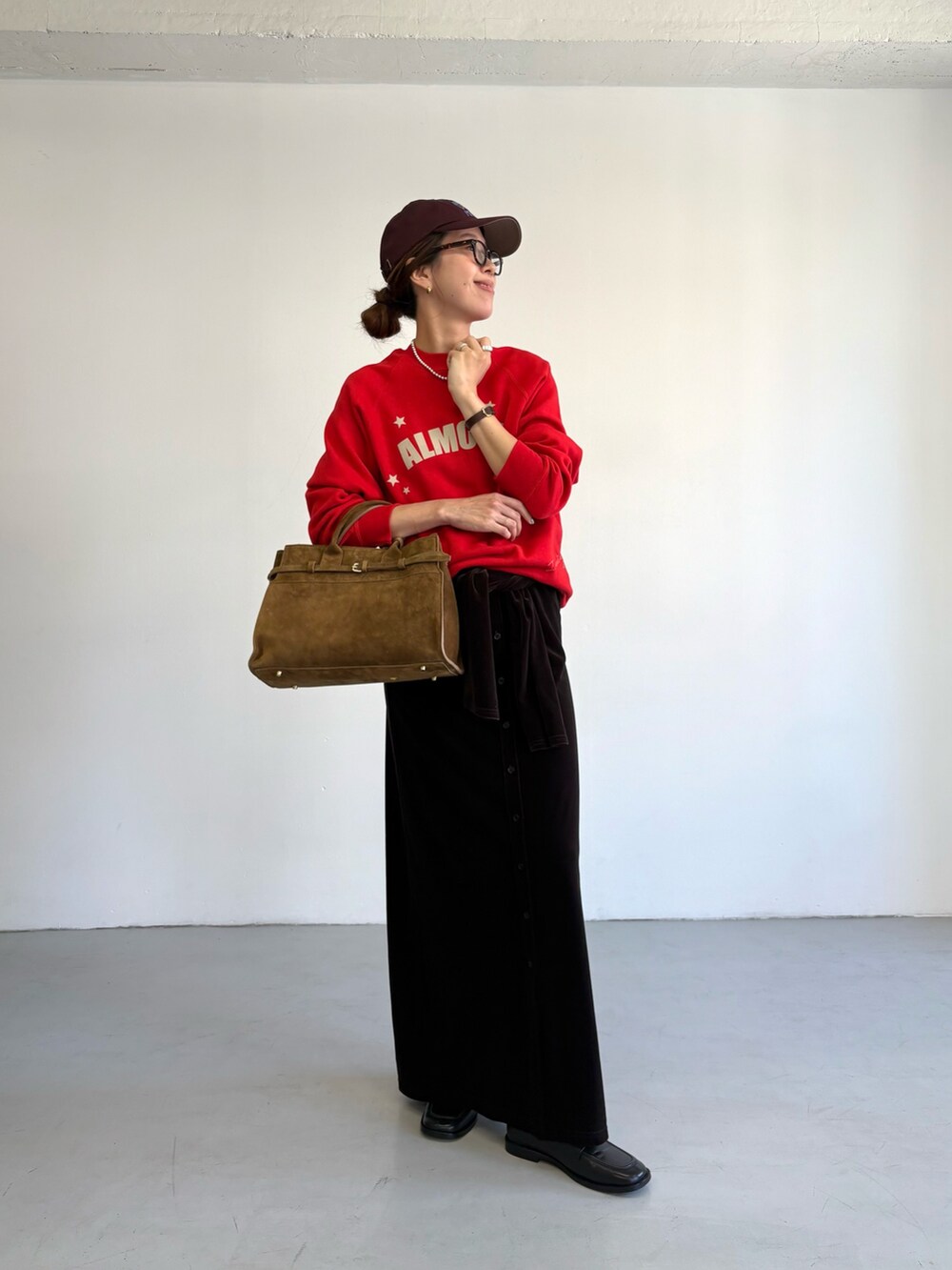 レッド系のスウェット、ブラウン系のトートバッグ、ブラック系のローファーを着用したレディースの秋コーディネートの2枚目の写真