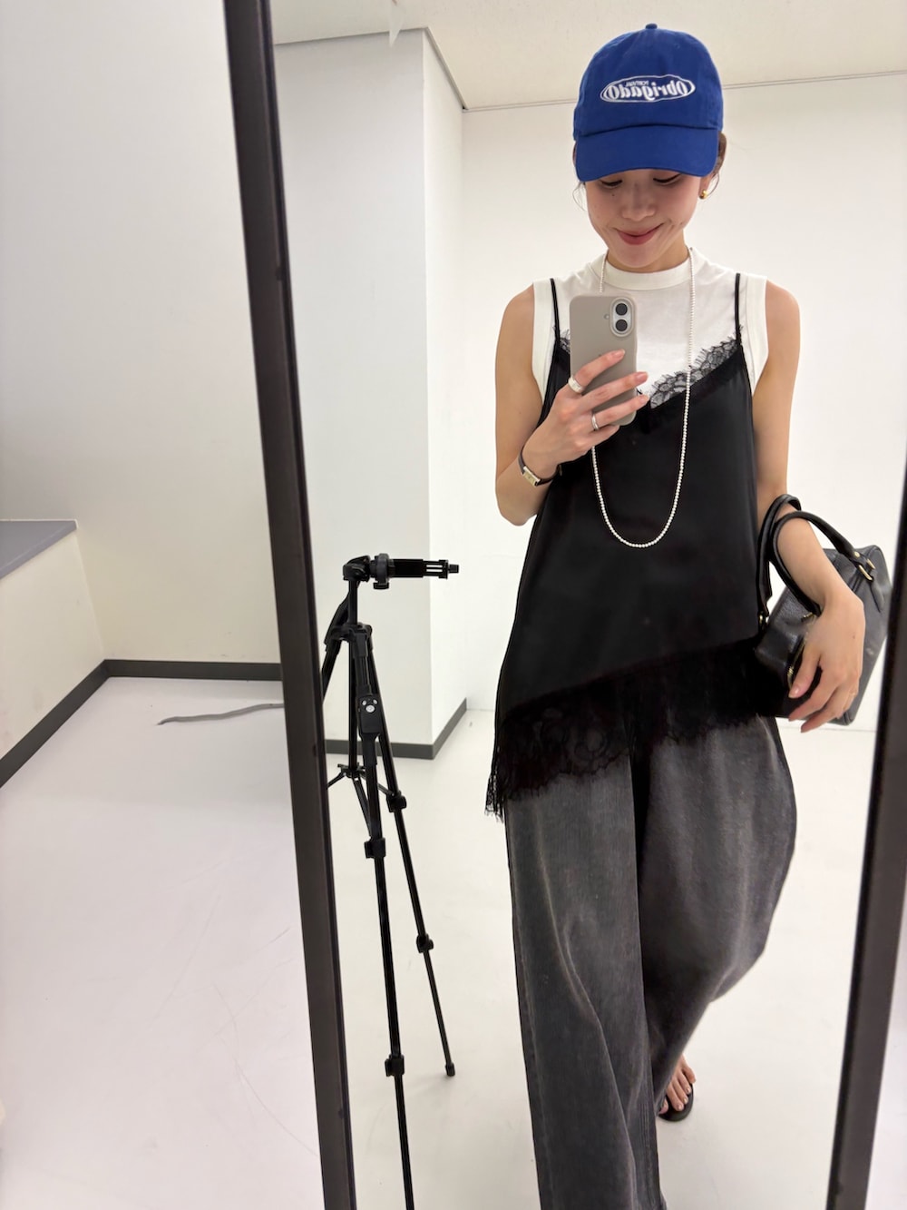 ブラック系のキャミソール、ホワイト系のタンクトップ、ブラック系のデニムパンツを着用したレディースの夏コーディネートの7枚目の写真