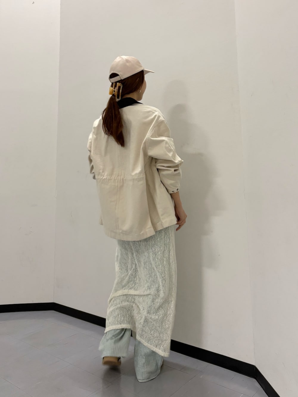 ベージュ系のカバーオール、ホワイト系のスカート、ホワイト系のスニーカーを着用したレディースの冬コーディネートの3枚目の写真