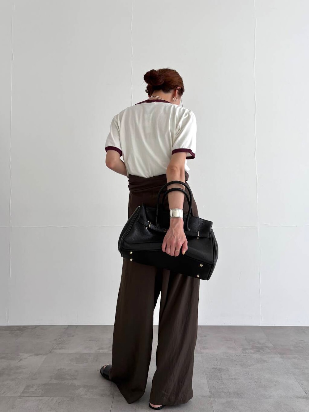 ブラウン系のサロペット/オーバーオール、ホワイト系のTシャツ/カットソー、ブラック系のサンダルを着用したレディースの春コーディネートの4枚目の写真