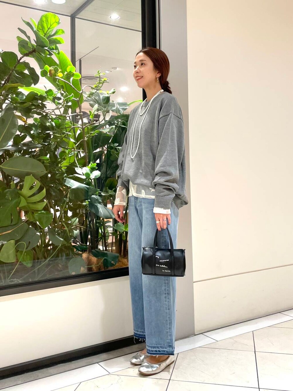 グレー系のニット/セーター、ブルー系のデニムパンツを着用したレディースの秋コーディネートの2枚目の写真