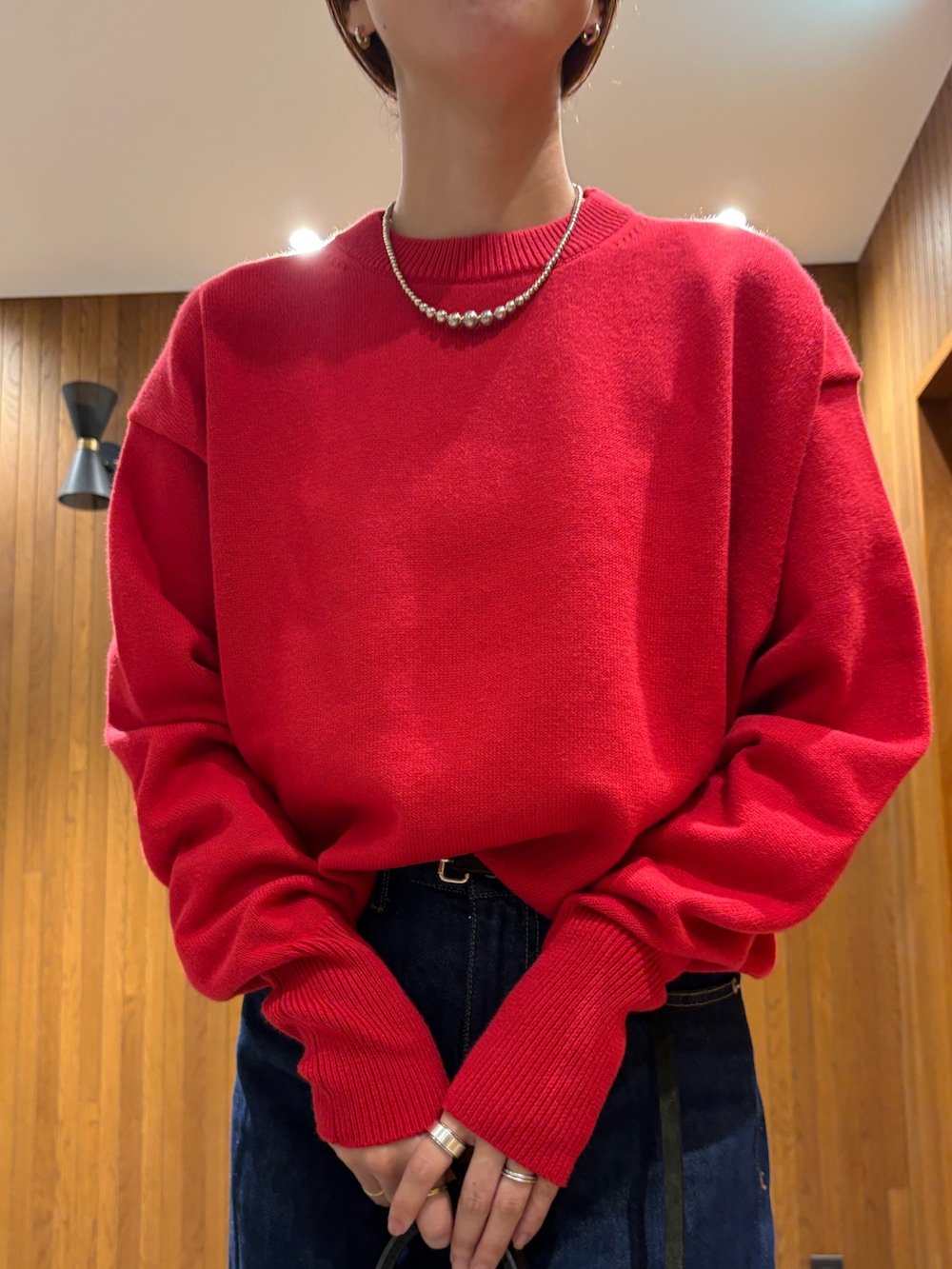 ブルー系のデニムパンツ、レッド系のニット/セーター、ブラック系のハンドバッグを着用したレディースの秋コーディネートの8枚目の写真