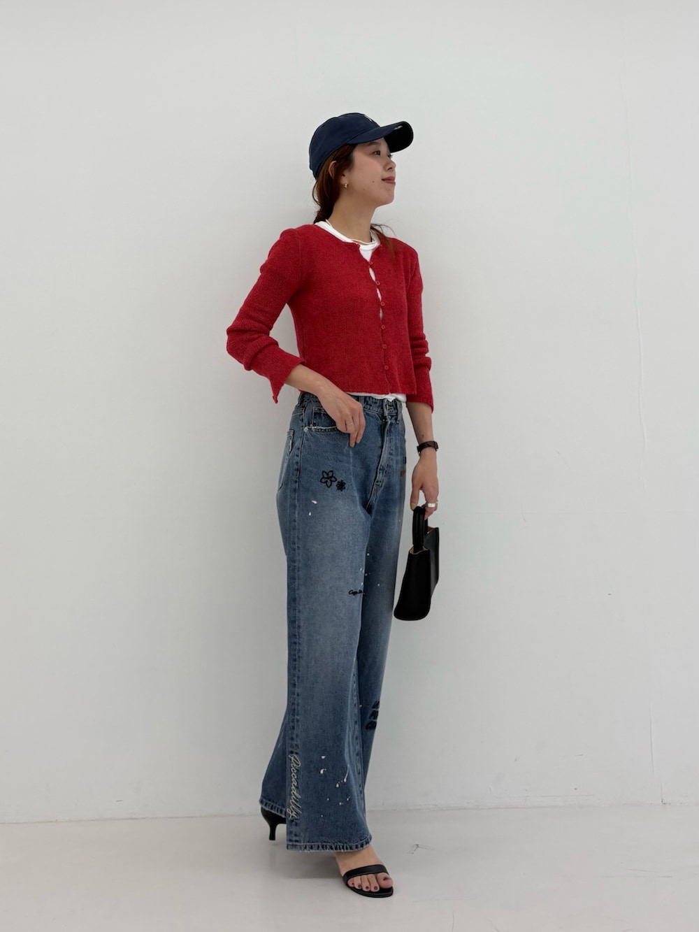 ブルー系のデニムパンツ、ホワイト系のTシャツ/カットソー、ブラック系のハンドバッグを着用したレディースの夏コーディネートの6枚目の写真