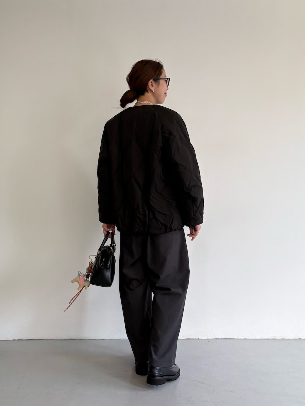 ブラック系のダウンジャケット/コート、グレー系のその他パンツ、ブラック系のローファーを着用したレディースの冬コーディネートの5枚目の写真