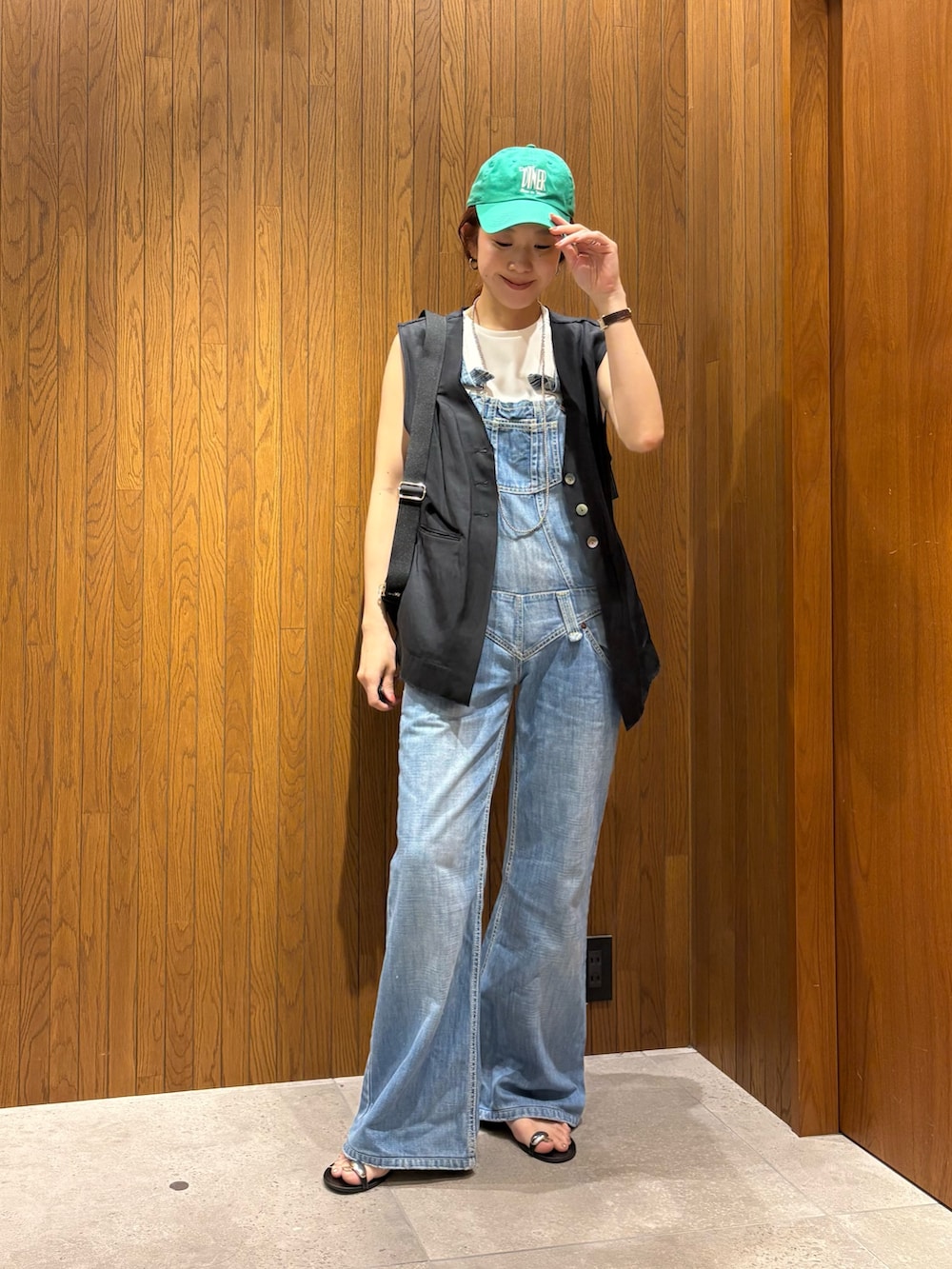 ブラック系のダウンベスト、ブラック系のショルダーバッグ、ホワイト系のTシャツ/カットソーを着用したレディースの夏コーディネートの5枚目の写真