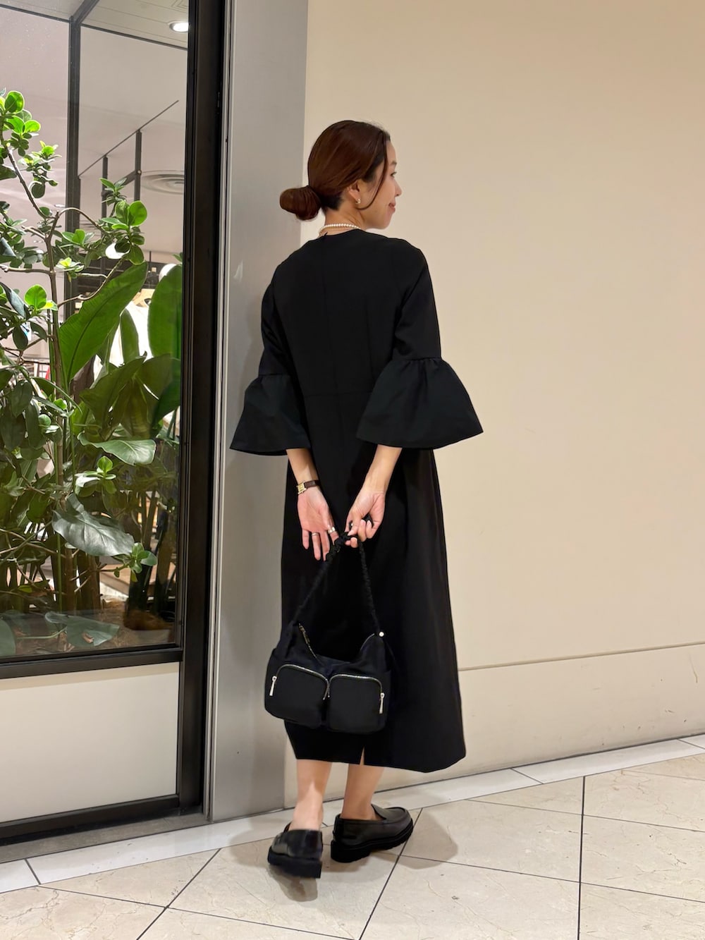 ブラック系のワンピース、ブラック系のローファー、ブラック系のショルダーバッグを着用したレディースの冬コーディネートの4枚目の写真