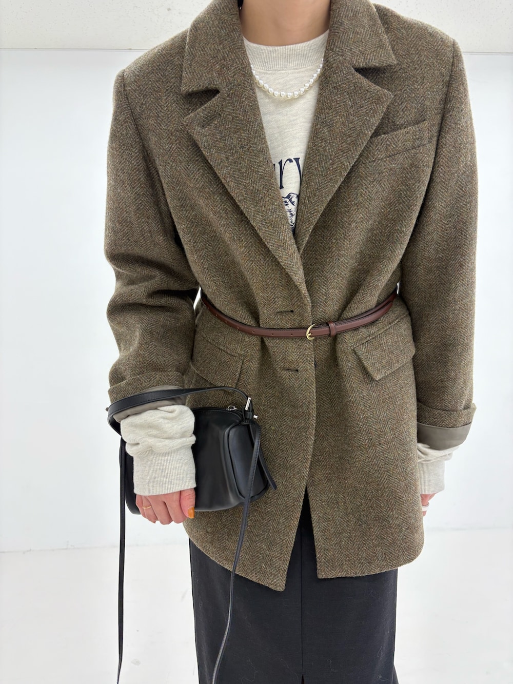 ブラック系のスカート、ブラック系のショルダーバッグ、グリーン系のその他アウターを着用したレディースの秋コーディネートの7枚目の写真