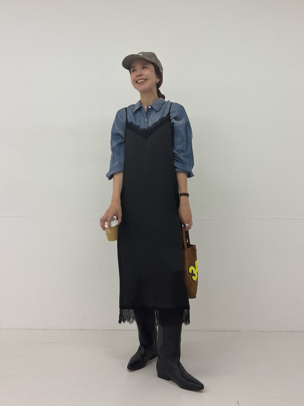 ブラック系のワンピース、ブラウン系のトートバッグ、ブラック系のブーツを着用したレディースの秋コーディネートの6枚目の写真