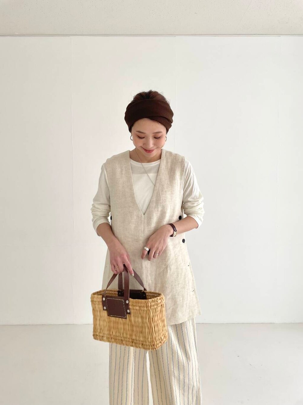 ベージュ系のベスト、ブラウン系のかごバッグ、ベージュ系のその他パンツを着用したレディースの春コーディネートの4枚目の写真