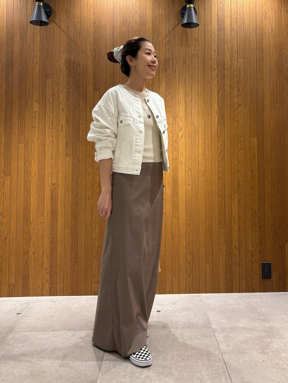 グレー系のスカート、ホワイト系のTシャツ/カットソー、ベージュ系のハンドバッグを着用したレディースの春コーディネートの2枚目の写真