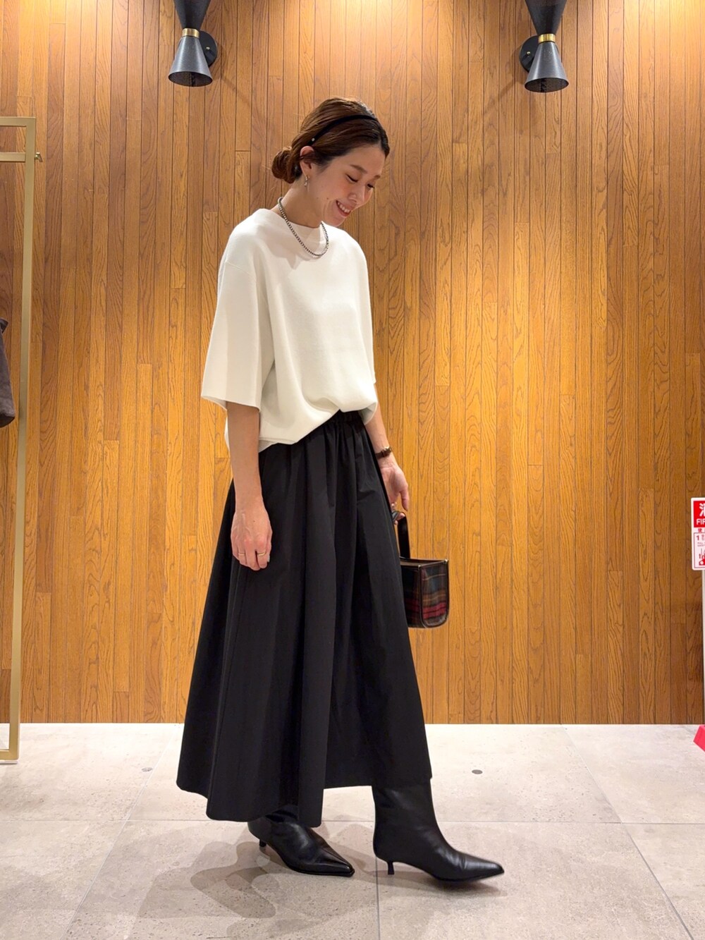 ホワイト系のニット/セーター、ブラック系のブーツ、ブラック系のスカートを着用したレディースの秋コーディネートの5枚目の写真