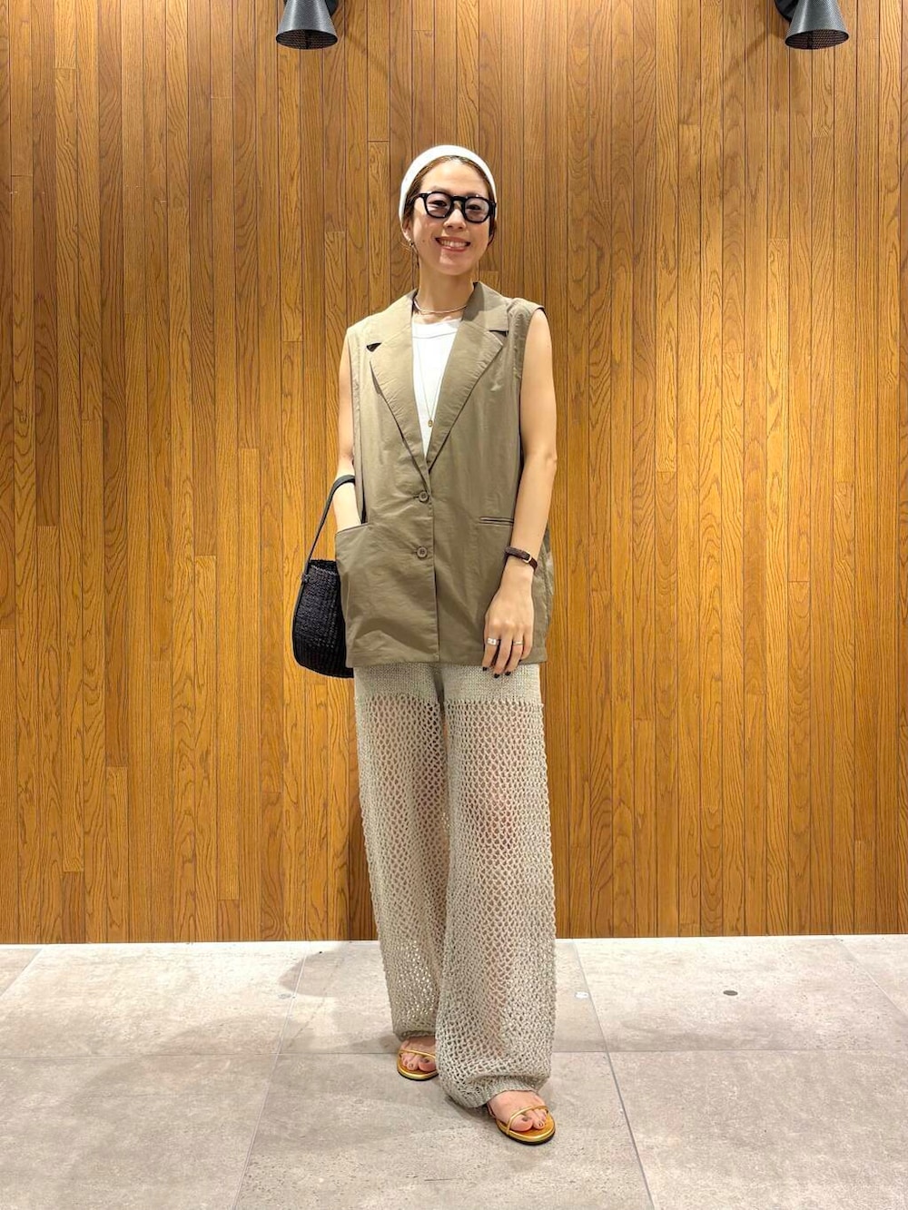 ブラック系のかごバッグ、ゴールド系のサンダル、グレー系のその他パンツを着用したレディースの夏コーディネートの5枚目の写真