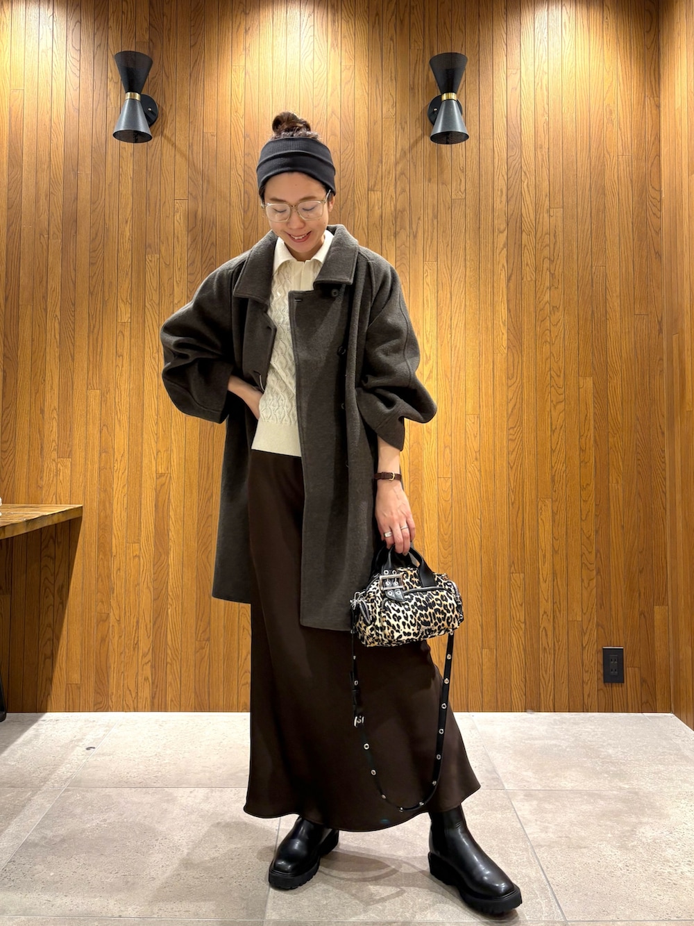 グリーン系のステンカラーコート、ブラウン系のスカート、その他のハンドバッグを着用したレディースの冬コーディネートの2枚目の写真