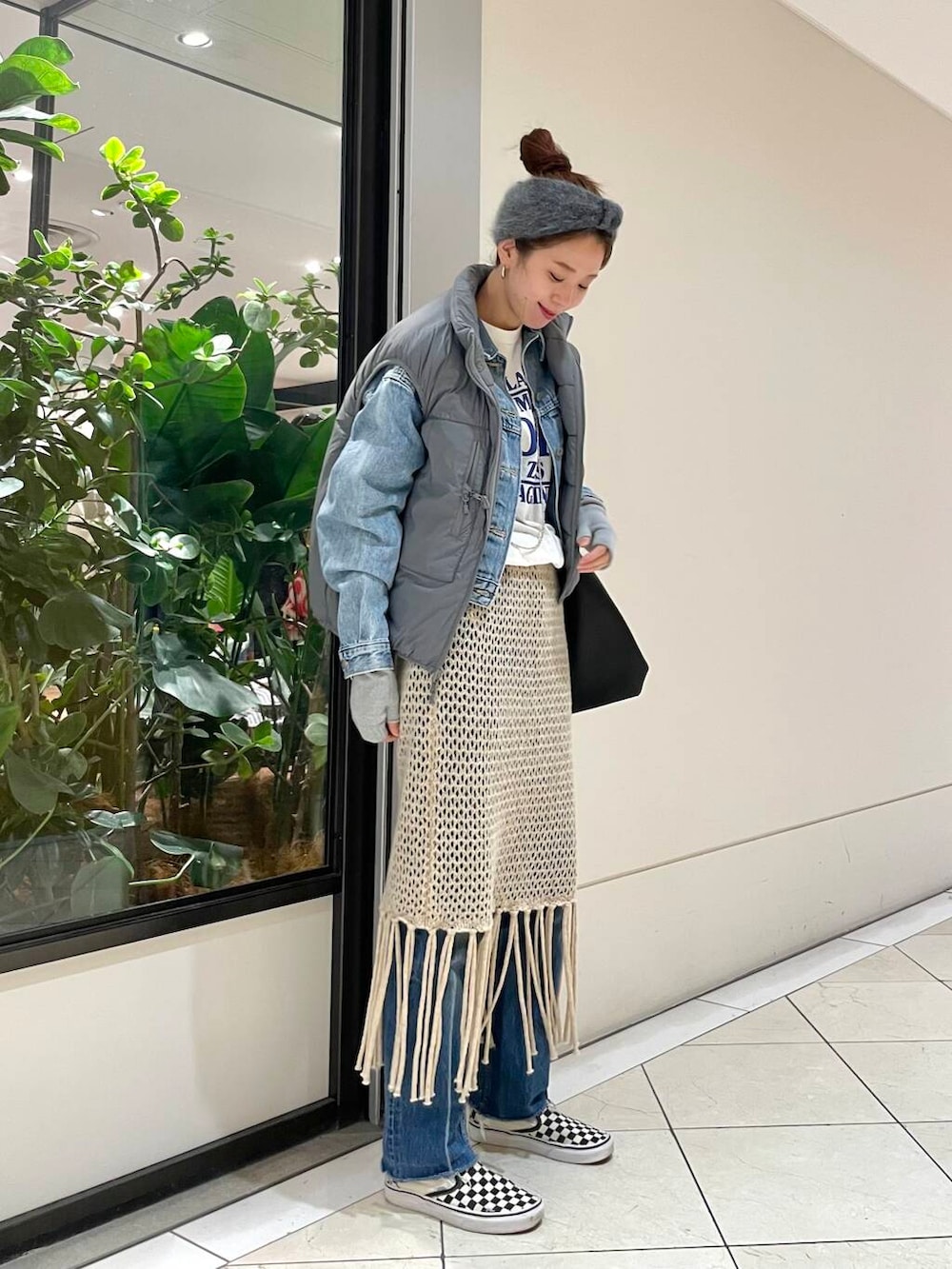 ベージュ系のスカート、ホワイト系のTシャツ/カットソー、グレー系のダウンベストを着用したレディースの冬コーディネートの2枚目の写真