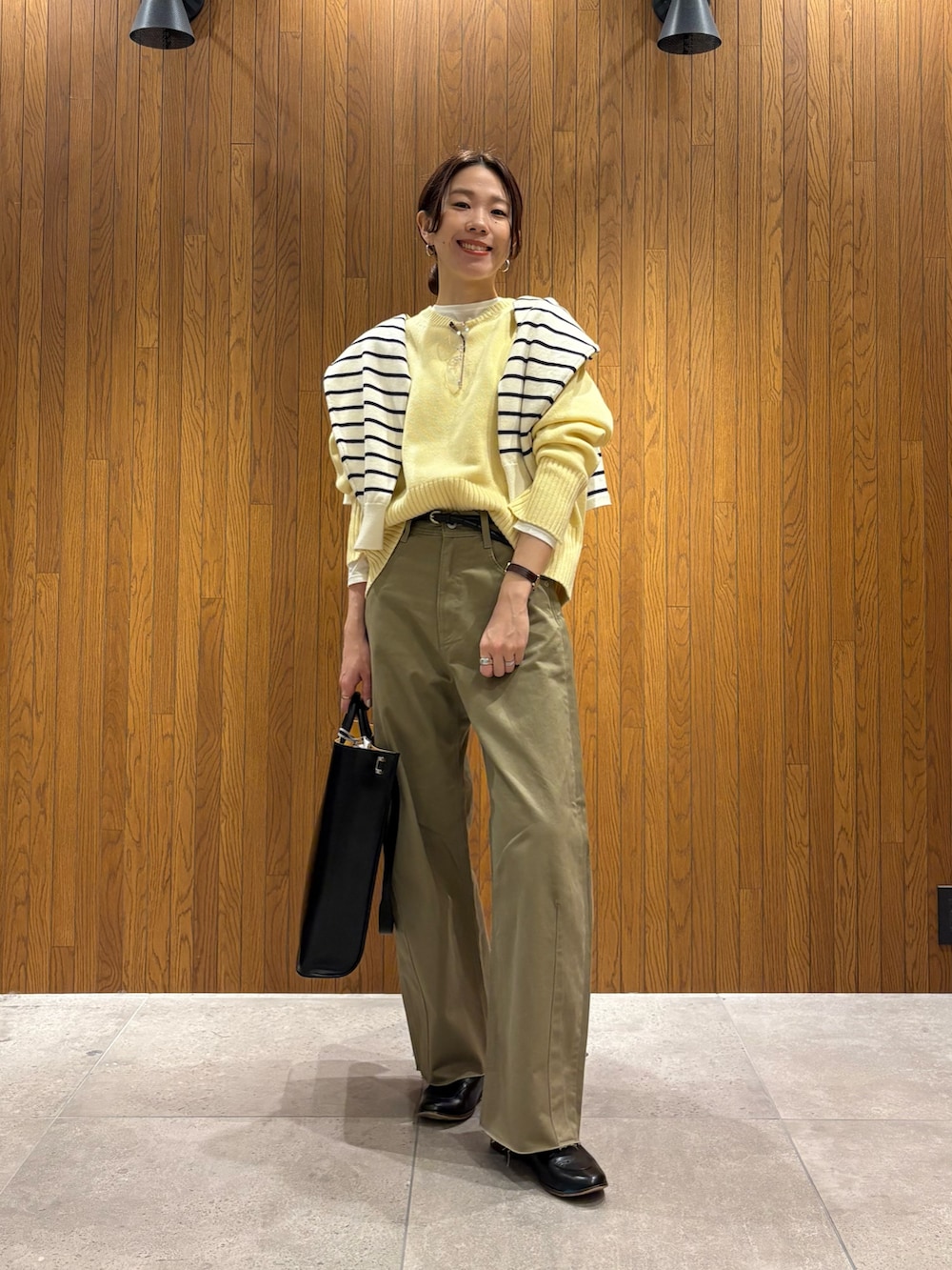 イエロー系のニット/セーター、ベージュ系のその他パンツ、ブラック系のハンドバッグを着用したレディースの冬コーディネートの4枚目の写真