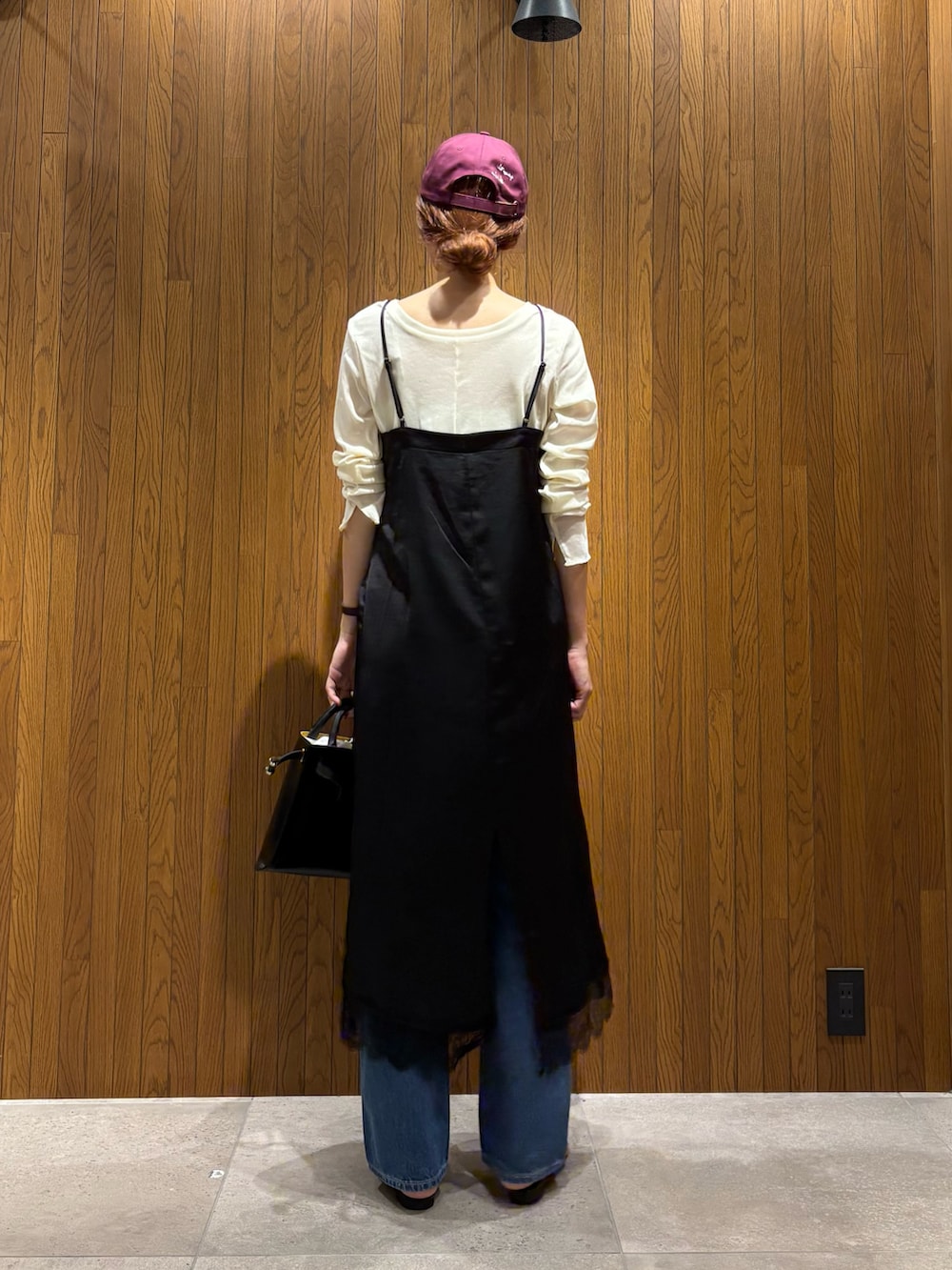 ブラック系のワンピース、ブルー系のデニムパンツ、ブラック系のショルダーバッグを着用したレディースの秋コーディネートの3枚目の写真