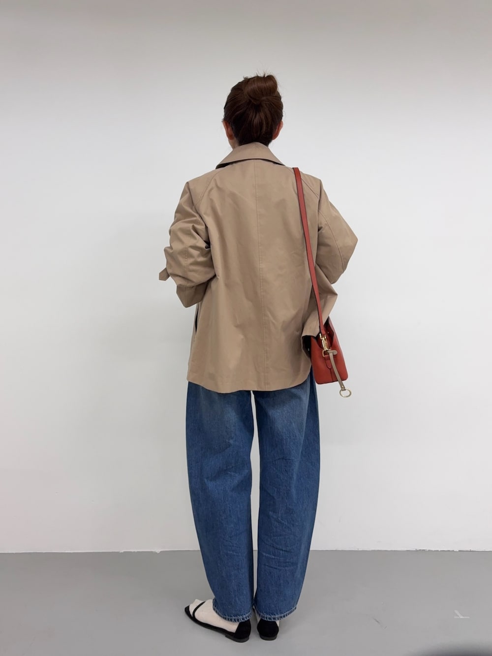 ベージュ系のトレンチコート、ブルー系のデニムパンツ、オレンジ系のショルダーバッグを着用したレディースの冬コーディネートの3枚目の写真