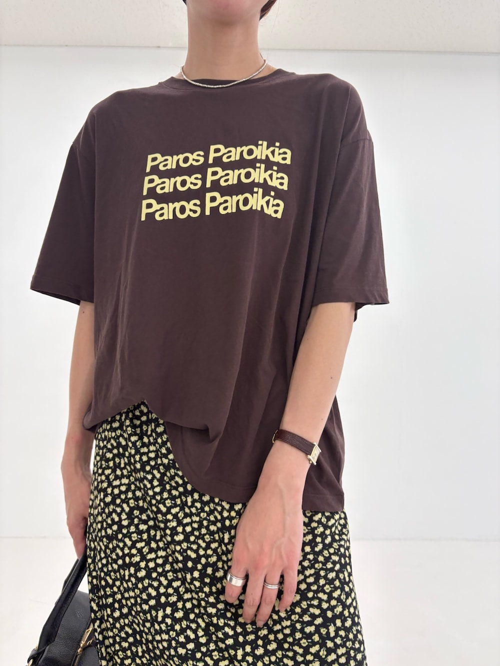ブラウン系のTシャツ/カットソー、イエロー系のスカート、ブラック系のハンドバッグを着用したレディースの夏コーディネートの5枚目の写真