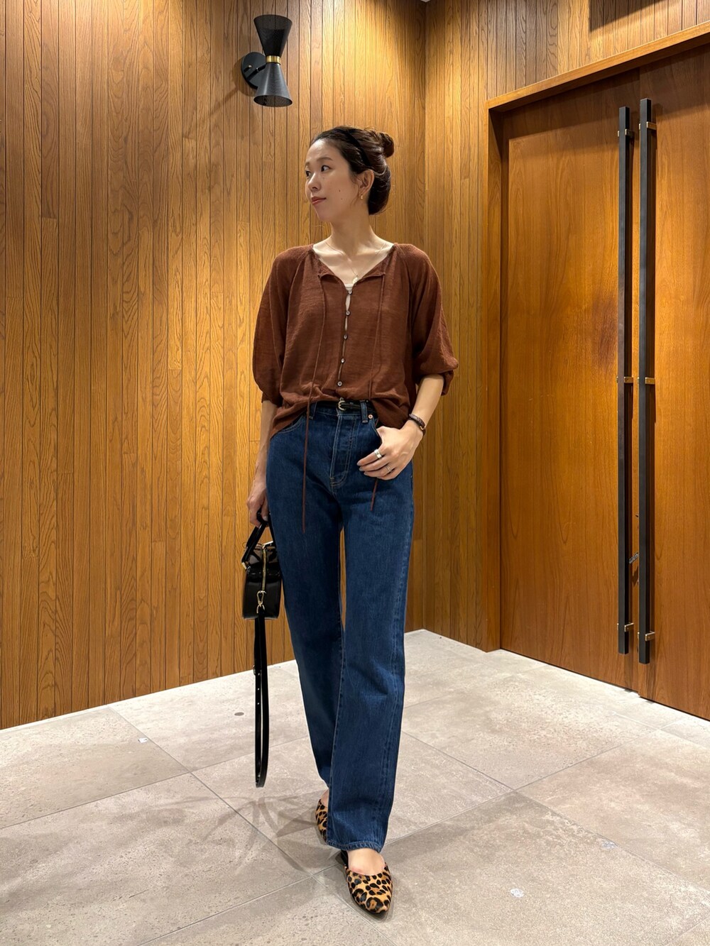 ブルー系のデニムパンツ、ブラック系のショルダーバッグ、ブラウン系のカーディガン/ボレロを着用したレディースの秋コーディネートの6枚目の写真