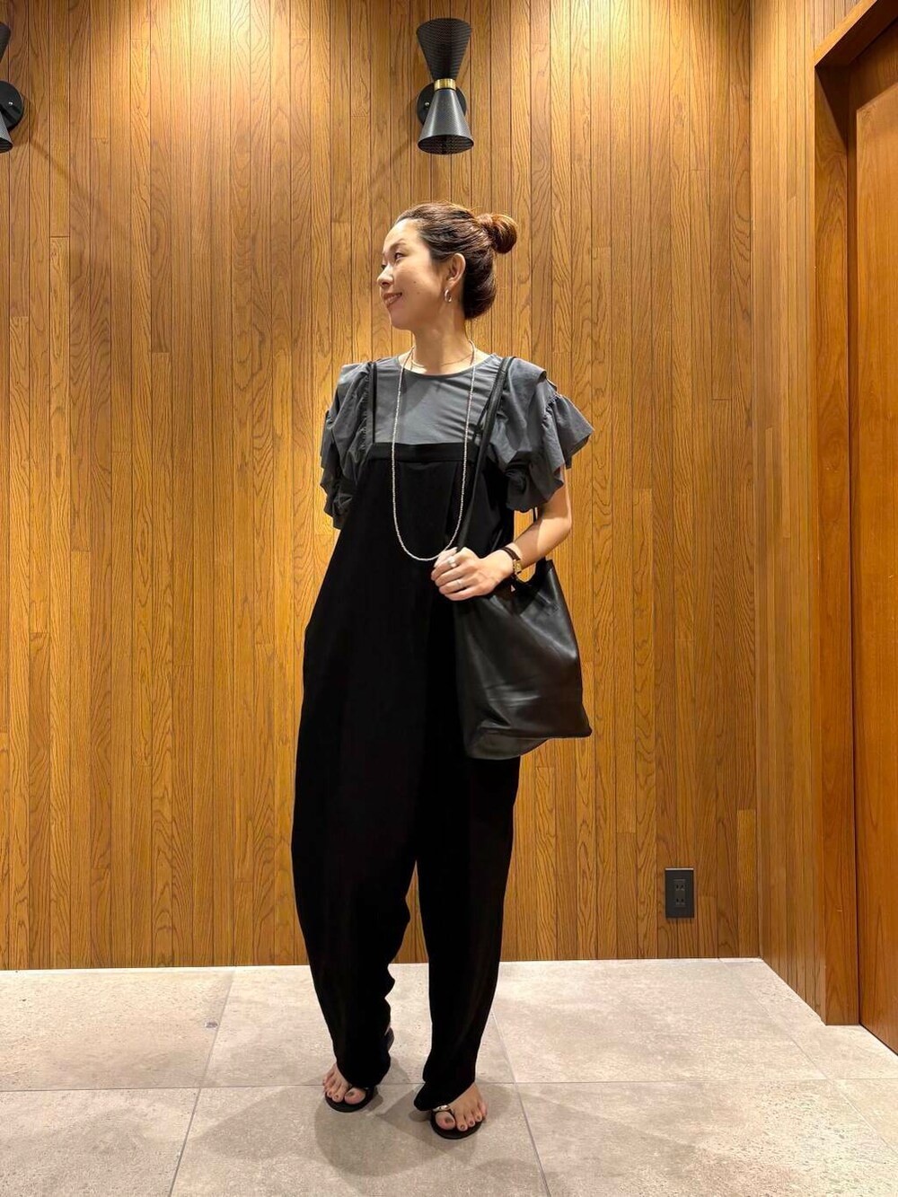 ブラック系のサロペット/オーバーオール、ブルー系のTシャツ/カットソー、ブラック系のサンダルを着用したレディースの夏コーディネートの6枚目の写真