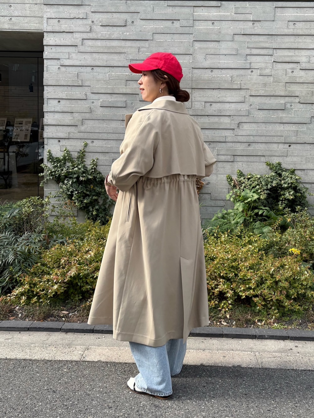 ベージュ系のトレンチコート、グレー系のデニムパンツ、ブラック系のショルダーバッグを着用したレディースの冬コーディネートの3枚目の写真