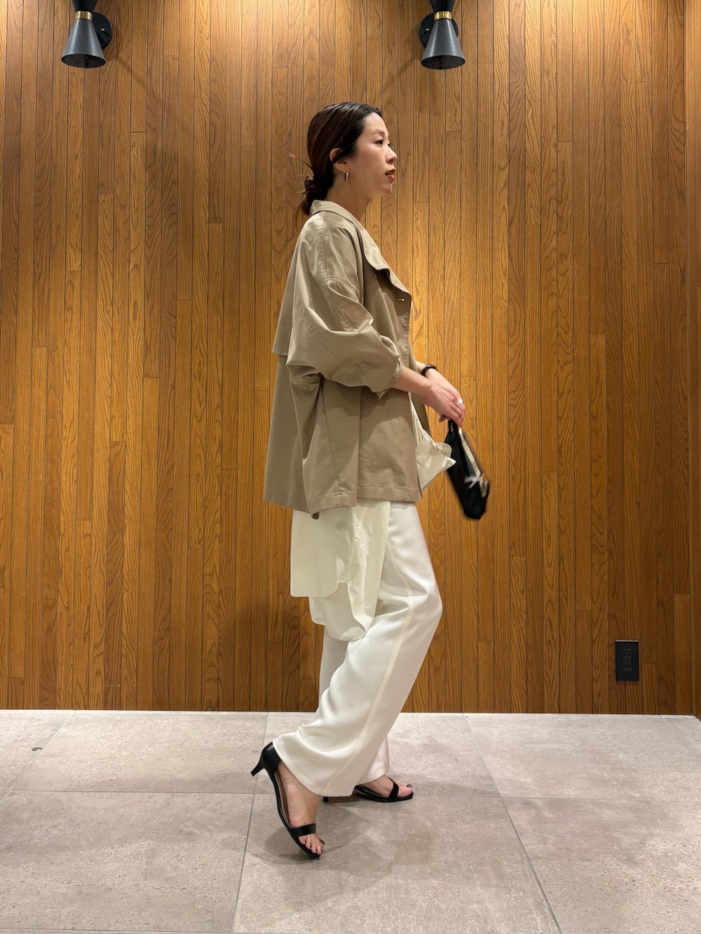 ベージュ系のトレンチコート、イエロー系のニット/セーター、ホワイト系のその他パンツを着用したレディースの春コーディネートの2枚目の写真