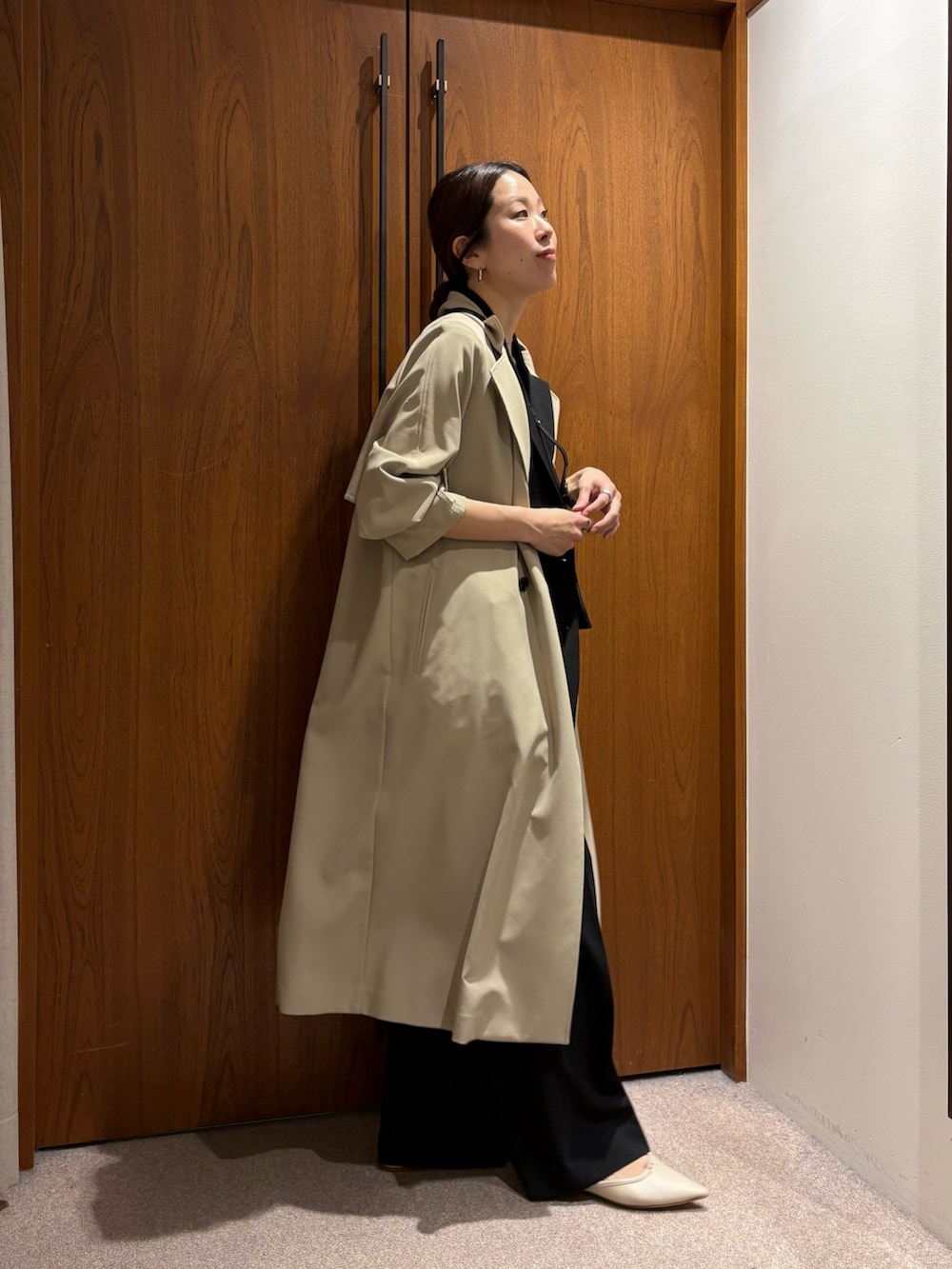 ベージュ系のトレンチコート、ブラック系のその他パンツ、ブラック系のその他アウターを着用したレディースの冬コーディネートの3枚目の写真