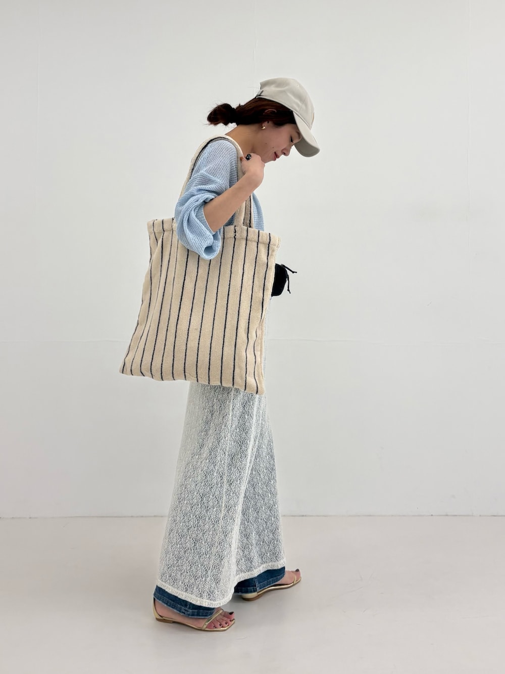 ブルー系のニット/セーター、ホワイト系のスカート、ブラック系のボディバッグ/ウエストポーチを着用したレディースの春コーディネートの3枚目の写真