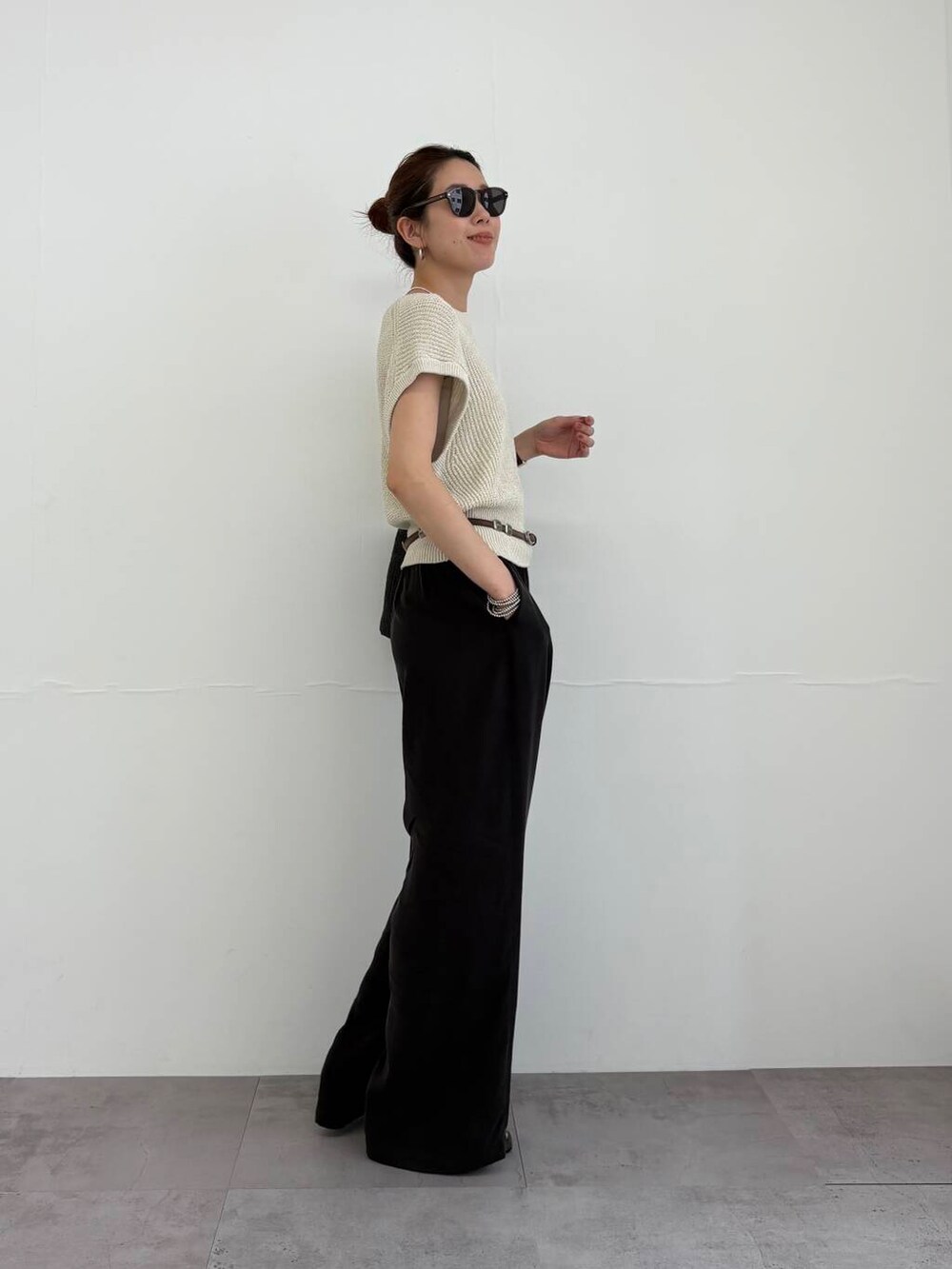 ブラック系のかごバッグ、ブラック系のサンダル、ベージュ系のベストを着用したレディースの夏コーディネートの2枚目の写真