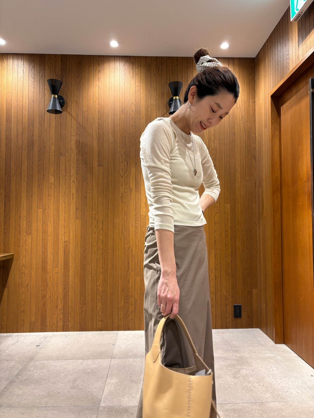 グレー系のスカート、ホワイト系のTシャツ/カットソー、ベージュ系のハンドバッグを着用したレディースの春コーディネートの10枚目の写真