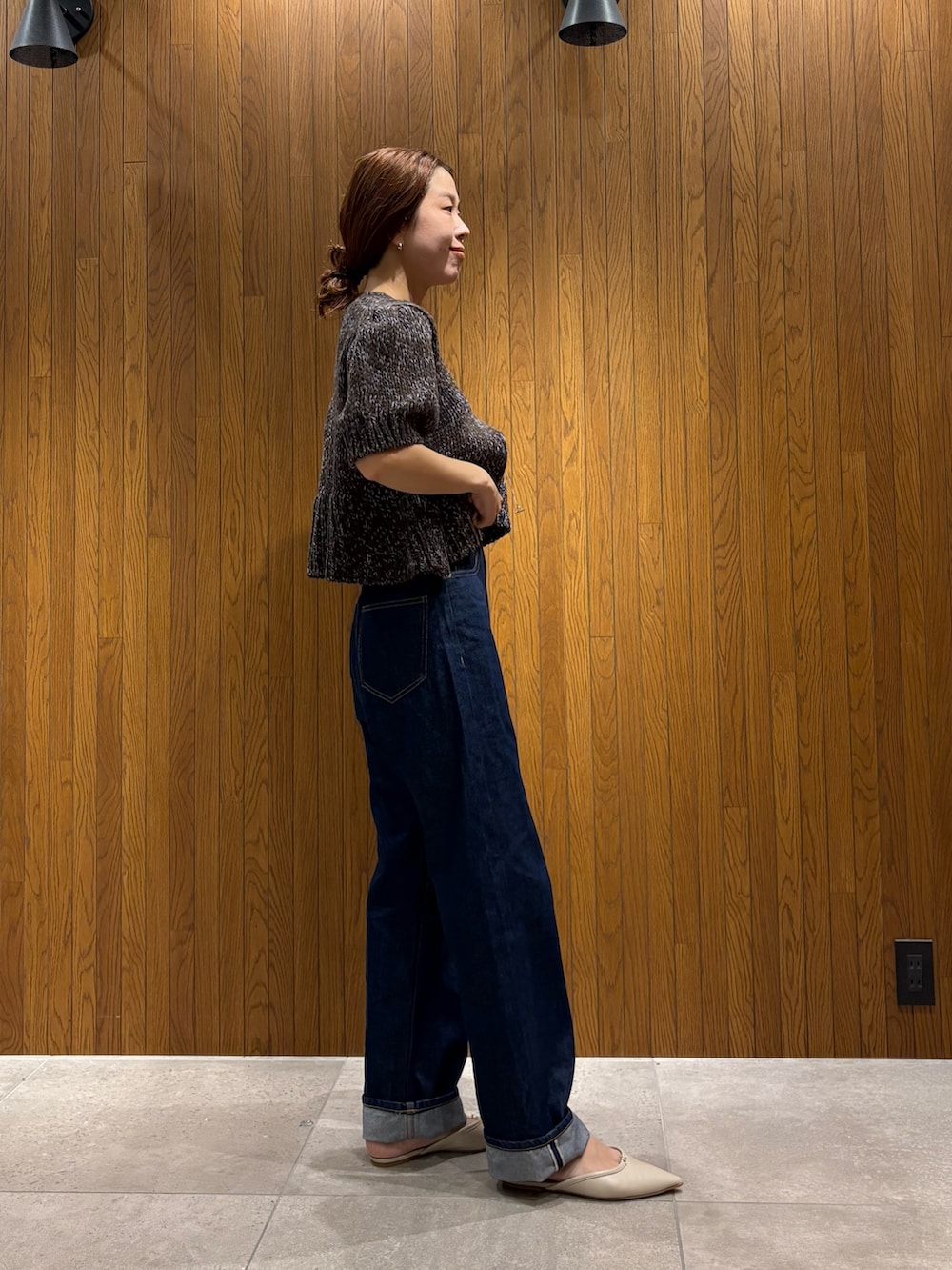 ブルー系のデニムパンツ、ブラウン系のニット/セーター、ベージュ系のハンドバッグを着用したレディースの秋コーディネートの5枚目の写真