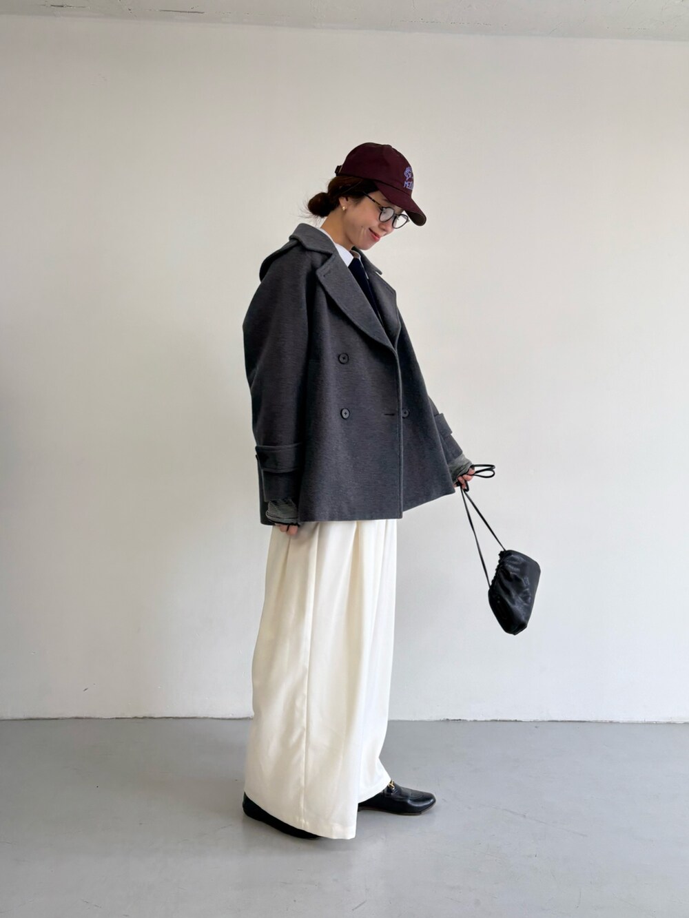 グレー系のピーコート、ホワイト系のその他パンツ、シルバー系のショルダーバッグを着用したレディースの冬コーディネートの3枚目の写真