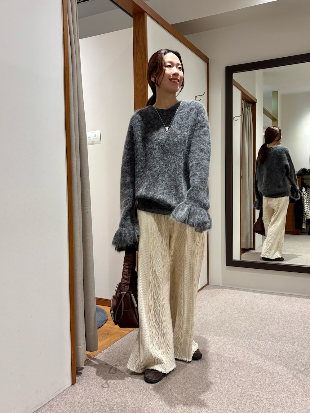 レッド系のショルダーバッグ、グレー系のニット/セーターを着用したレディースの冬コーディネートの2枚目の写真