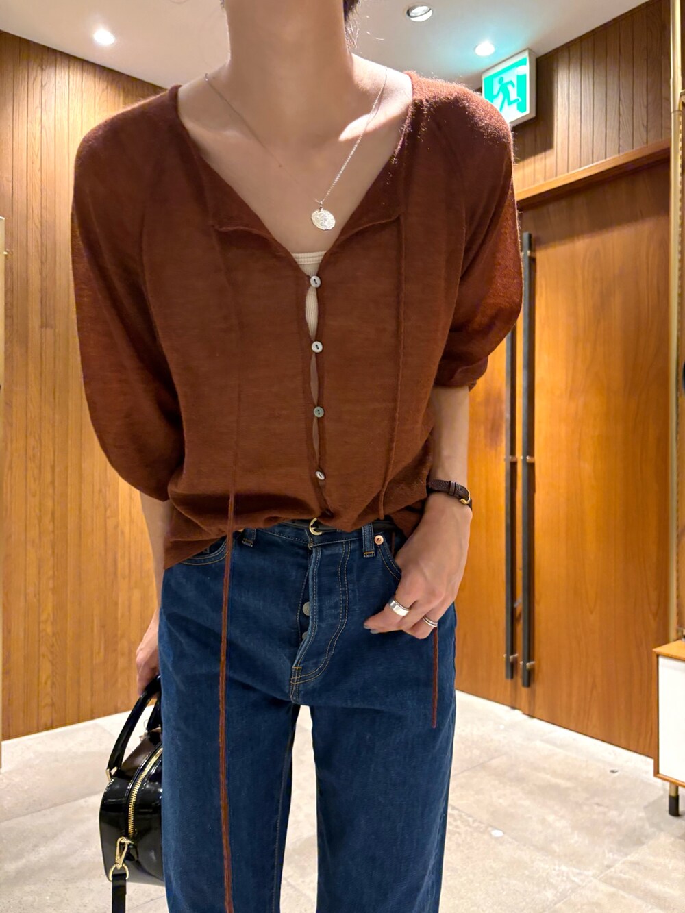 ブルー系のデニムパンツ、ブラック系のショルダーバッグ、ブラウン系のカーディガン/ボレロを着用したレディースの秋コーディネートの7枚目の写真