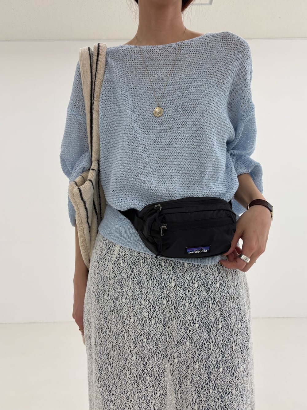 ブルー系のニット/セーター、ホワイト系のスカート、ブラック系のボディバッグ/ウエストポーチを着用したレディースの春コーディネートの6枚目の写真