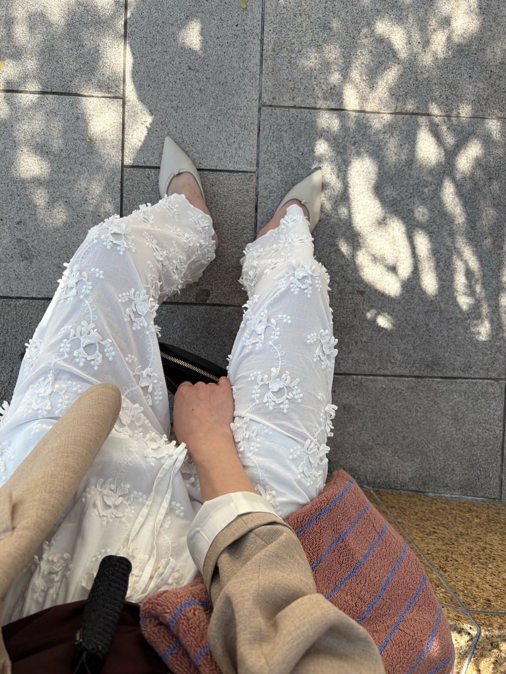 ベージュ系のその他アウター、ホワイト系のその他パンツ、ブラック系のハンドバッグを着用したレディースの春コーディネートの8枚目の写真