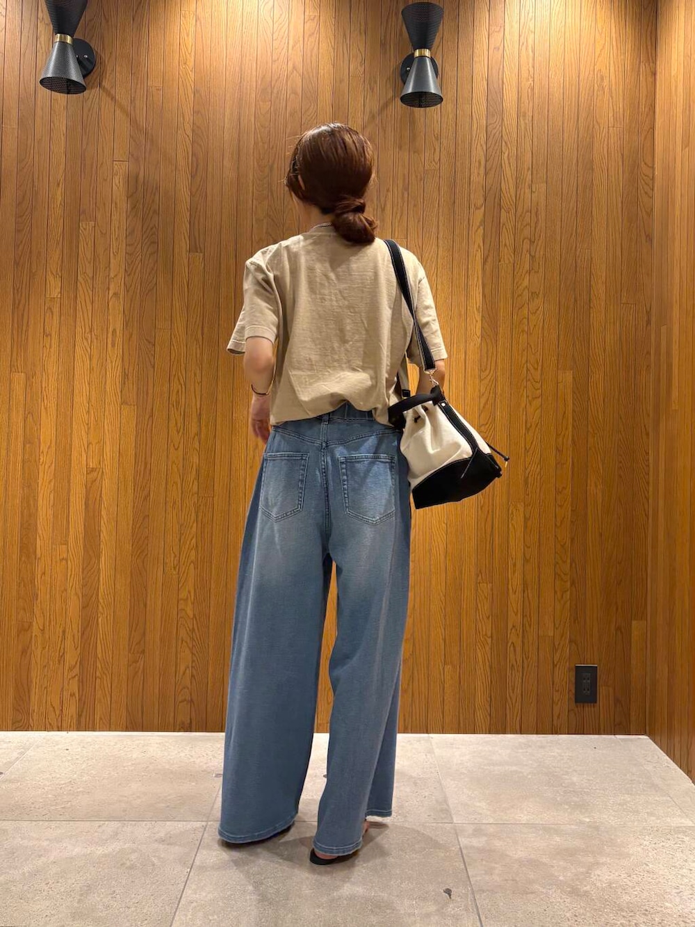 ブルー系のデニムパンツ、ブラック系のサンダル、ベージュ系のTシャツ/カットソーを着用したレディースの夏コーディネートの3枚目の写真