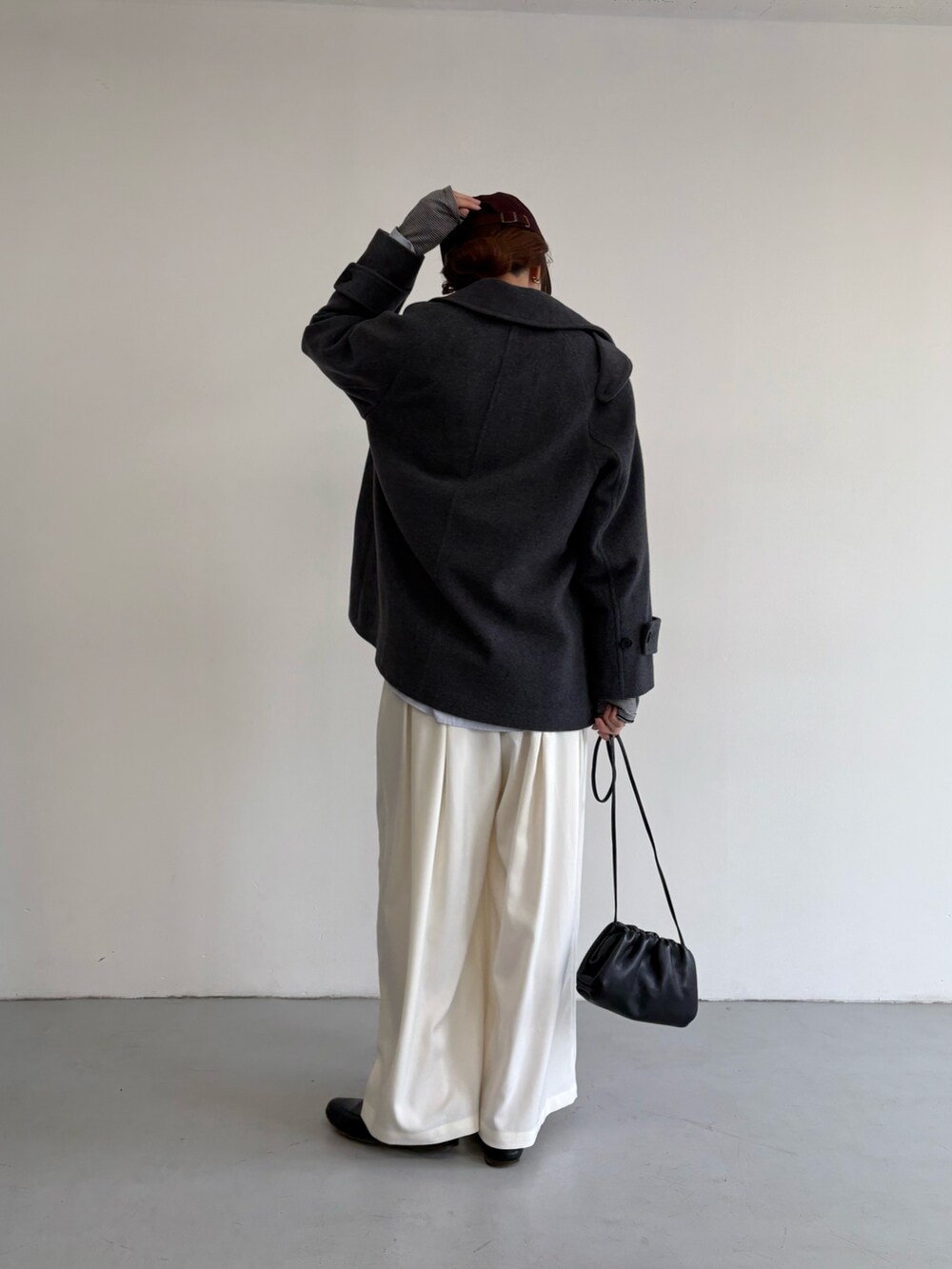 グレー系のピーコート、ホワイト系のその他パンツ、シルバー系のショルダーバッグを着用したレディースの冬コーディネートの4枚目の写真