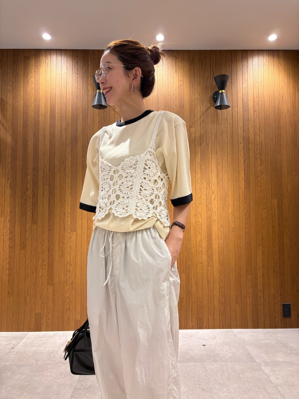 ホワイト系のニット/セーター、グレー系のその他パンツ、ブラック系のショルダーバッグを着用したレディースの夏コーディネートの7枚目の写真